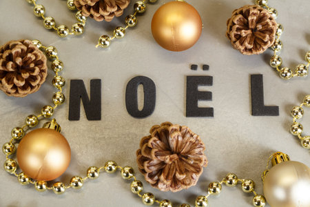 Golden christmas balls, pine cones and pearls tinsel with the word Christmas in frenchの写真素材