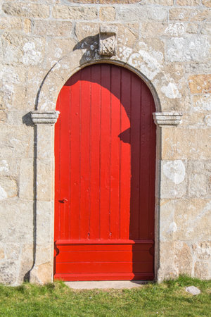 Red wooden door of Notre Dame de Bon Voyage chapel in Plogoffの写真素材