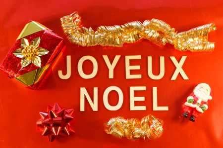 Merry Christmas written in french language with gift and Christmas decorations on red backgroundの写真素材