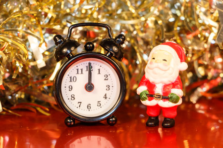 Santa Claus figurine, black vintage alarm clock and golden tinselの写真素材