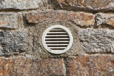 Round exterior ventilation grid made in plastic in the wall of an house