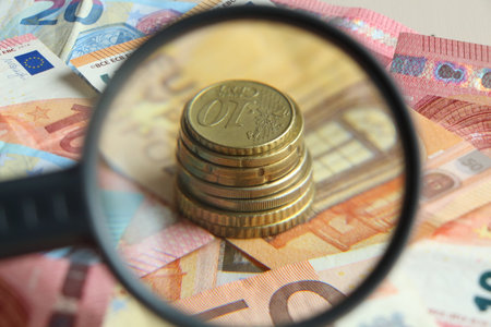 Euro coins, cents, notes and magnifying glassの写真素材