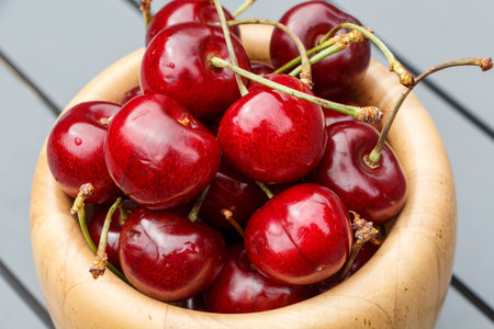 Cherries in a wooden bowl on a garden tableの写真素材