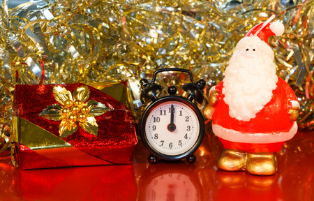 Santa Claus figurine, gift, alarm clock and golden tinselの写真素材