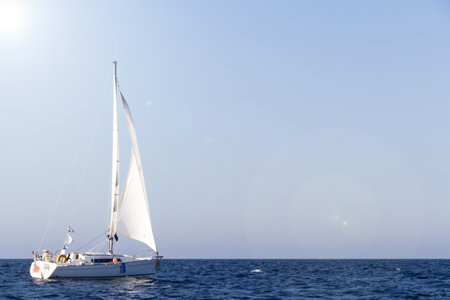 Sailboat with white sails under the sun in Brittany