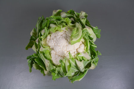 Raw fresh cauliflower with leaves on gray backgroundの写真素材