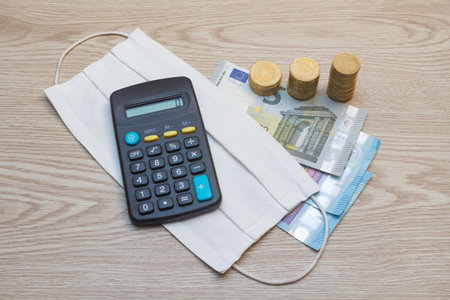 Fabric mask, money and calculator as concept for the price of protection against coronavirus