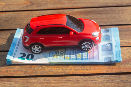 Red toy car on a heap of euros banknotesの写真素材