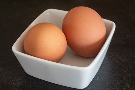 Two fresh eggs in a white ramekin