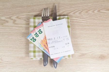 Fork, knife, napkin, euros banknotes and restaurant billの写真素材
