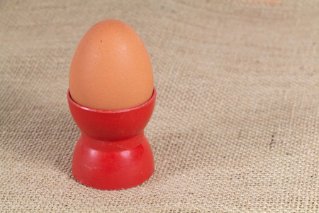 Soft-boiled egg in an eggcup on hessian background