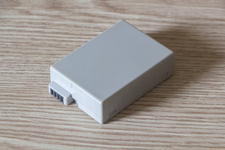 gray plastic camera battery on wooden background