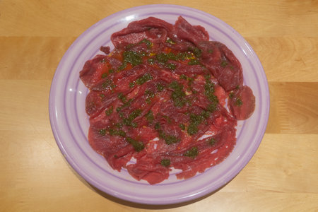 Carpaccio with oil and basil on a purple plateの写真素材