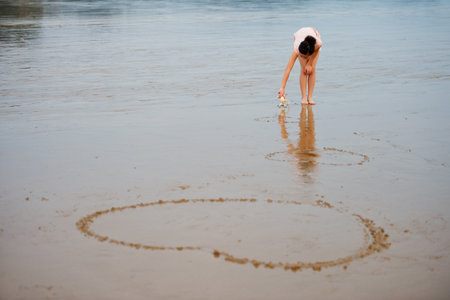 Girl on the beach with shells painted heartの写真素材