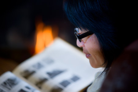 Woman sitting in living room by fireplaceの写真素材