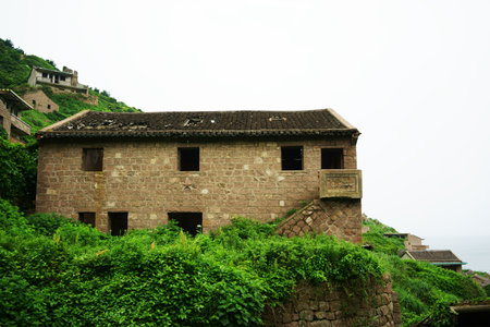 The decline of fisheries resources, China Zhejiang Shengsi Shengshan Island fishermen have relocated, becoming no village, abandoned houses covered with green plantsの写真素材