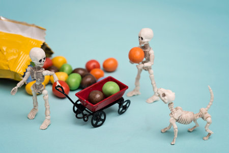 Two skeleton kids and skeleton dog getting chocolate candyの写真素材