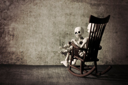 Skeleton and a little skeleton sitting in the rocking chair grungy texturedの写真素材