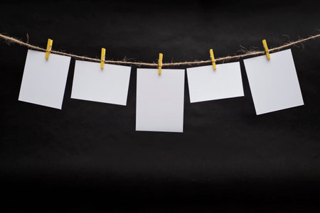 Rows of empty photo frames hanging with clothespins on dark backgroundの写真素材