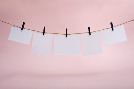 Rows of empty photo frames hanging with clothespins on pink background