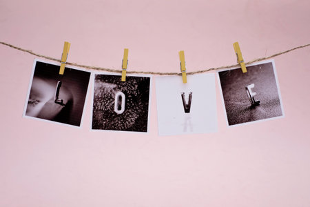 Rows of LOVE photo frames hanging with clothespins on pink backgroundの写真素材