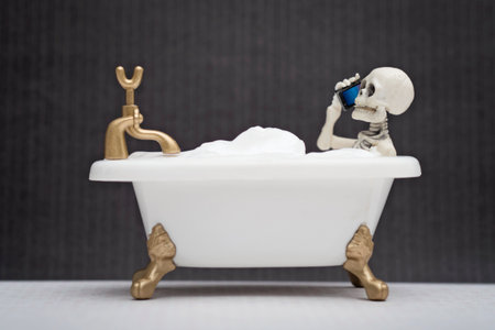 A skeleton talking on his cellphone while having bubble bathの写真素材