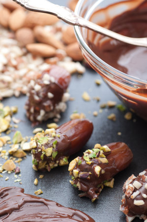 Dates dipped in melted chocolate and pistachio nuts almonds の写真素材