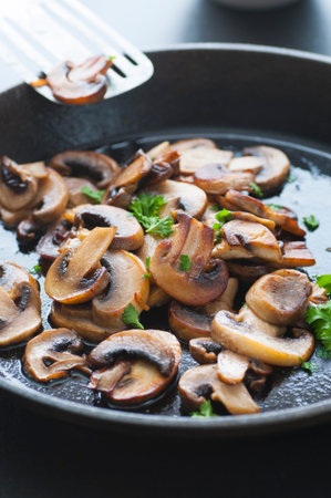 Butter fried sliced mushrooms with parsley in a pan.の写真素材