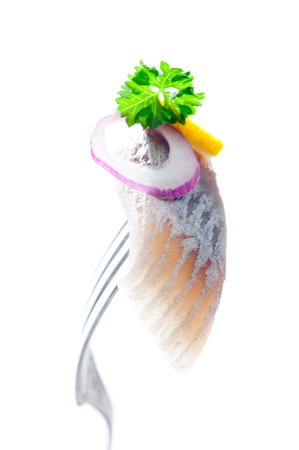 A piece of pickled herring on a fork.の写真素材