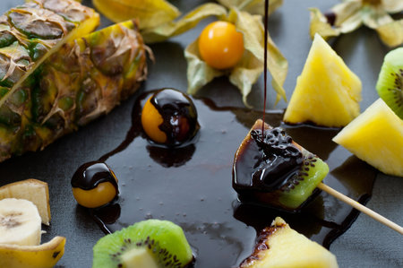 Fresh triopical fruits dipped in melted chocolate.の写真素材