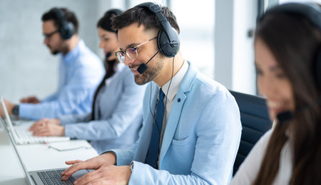Confident handsome call center operator assisting customers, engaged in conversation in the Call...