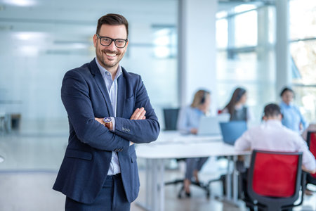 Handsome business CEO executive business man with crossed arms standing in office with colleagues in...