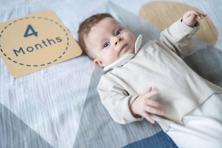 Top view of 4 month old adorable baby lying in bed and looking at camera.の写真素材