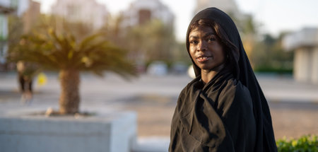 Portrait of beautiful muslim woman wearing traditional Abaya dress on city street at sunset.の写真素材