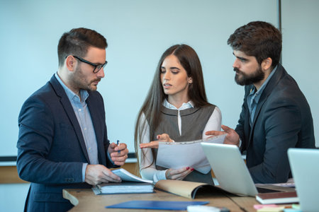 Mentor discussing papers with employee during a business meeting, helping employee with contract, pointing out mistakes.の写真素材