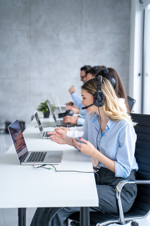 Vertical side view of beautiful blond hair call canter agent working with group of operators in office.の写真素材