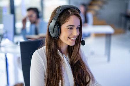 Closeup headshot of smiling young female customer support agent with headset at call center.