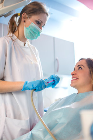 Female patient at the dentist. Female nurse preparing to put a suction tube into patients mouth