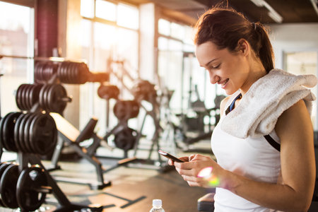 Active girl using smartphone in fitness gym.の写真素材