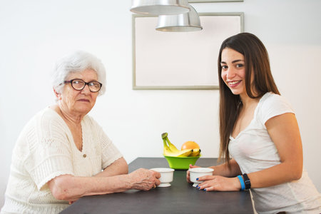 Granddaughter having a cup of tea with her grandmother at homeの写真素材