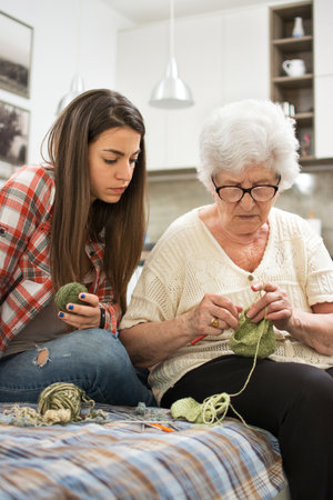 Grandmother showing granddaughter how to knit