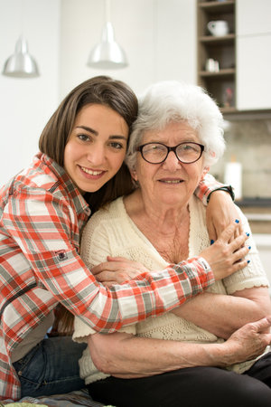 Portrait of granddaughter and grandmother hugging at home