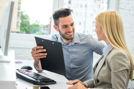 Handsome business man talking with attractive blonde woman in officeの写真素材