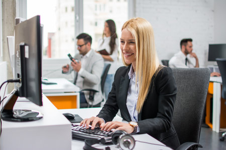 Smiling blonde young woman working in officeの写真素材