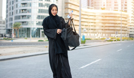 Beautiful muslim woman with water bottle and sports bag going to the gym.の写真素材