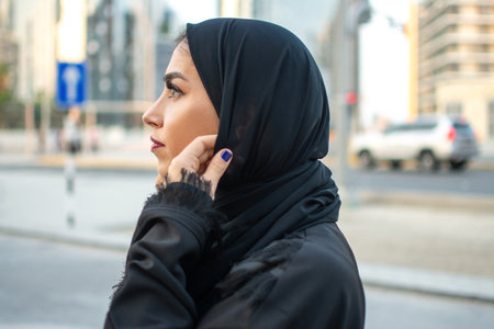 Side view of young muslim woman wearing traditional arabic clothing. Arabian woman holding veil with hands.の写真素材