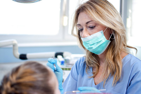 Female dentist with the tools in her hands is making a dental checkup to a patient at the dental clinic.の写真素材
