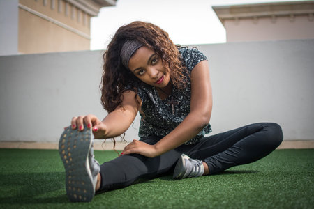 Beautiful young woman stretching her legs outdoors.の写真素材