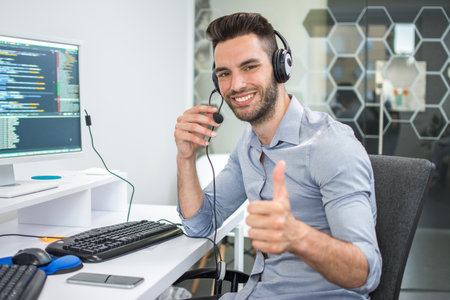 Smiling handsome man customer support operator showing thumb up.の写真素材