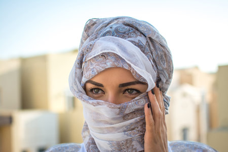 Headshot of Muslim girl dressed in traditional Arabic clothing outdoors.